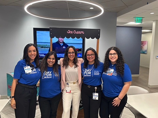 four women dressed in blue with a woman dressed in pink in their midst