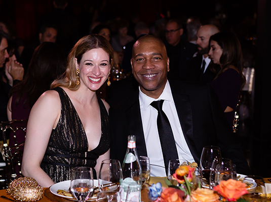 man and woman sitting at the table eating and smiling