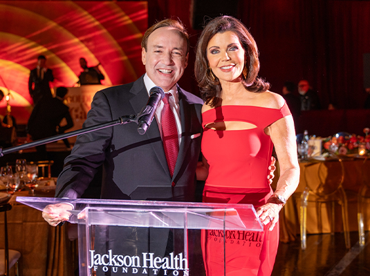 man and woman in front of a podium presenting an event
