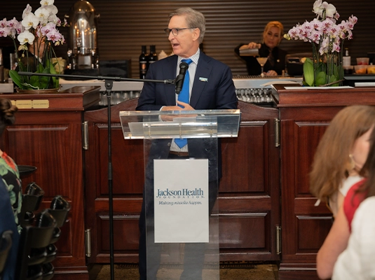 man speaking to the public from a platform with a microphone