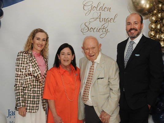 four people posing and smiling at the camera