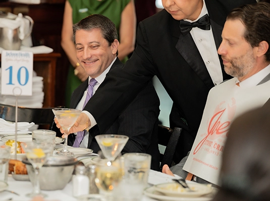 man having a cocktail and smiling during a formal event