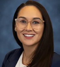 Close-up of a black-haired woman wearing glasses and a gray suit