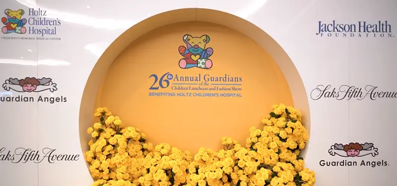 A backdrop that reads 26th Annual Guardians of the Children Luncheon and Fashion Show