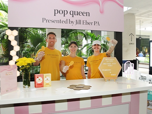 Three people behind a pink ice cream counter