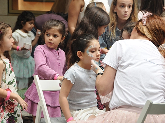 A woman painting faces on a group of children
