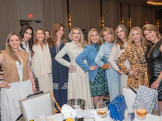 A large group of women wearing dresses, posing and smiling at the camera.