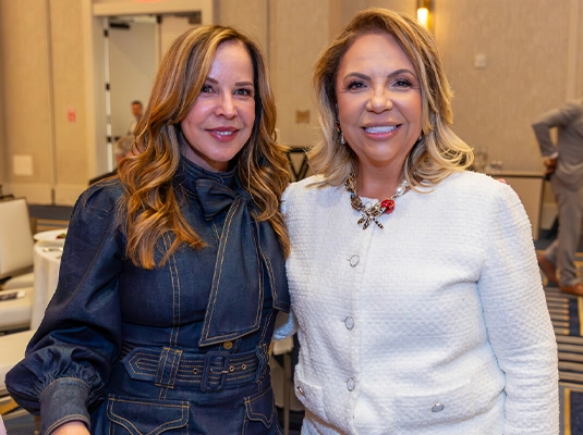 Two adult women smiling at the camera.