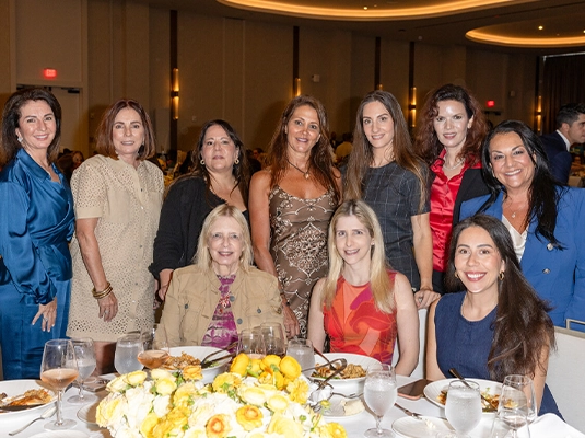 A large group of women wearing dresses, posing and smiling at the camera.