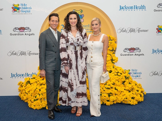 Three people dressed in formal attire posing for the camera during an event.