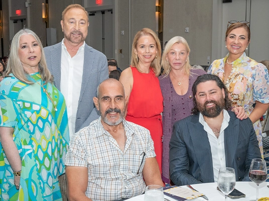 A group of people sitting at a table, posing for the camera.