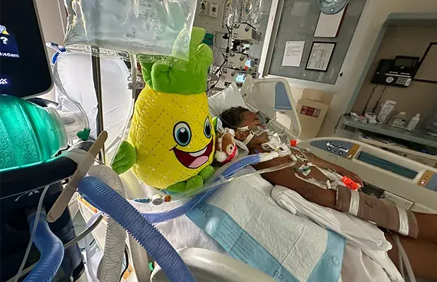 child lying on a hospital gurney next to a stuffed animal