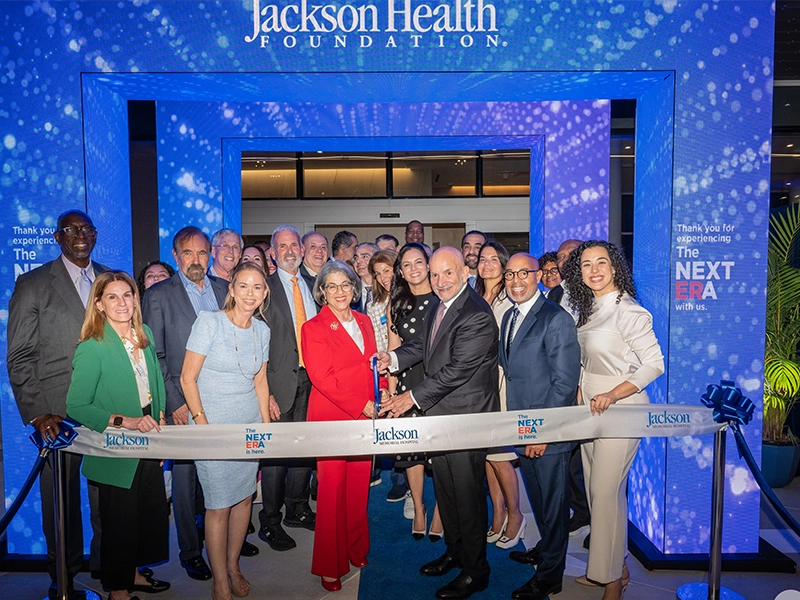 A group of people cutting a blue ribbon for the launch of a new venue.