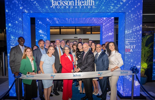 A group of people cutting a blue ribbon for the launch of a new venue.