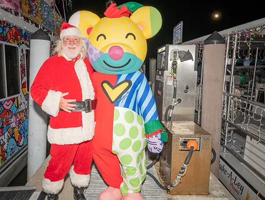 Santa Claus and a bear smiling at the camera, they are on a boat