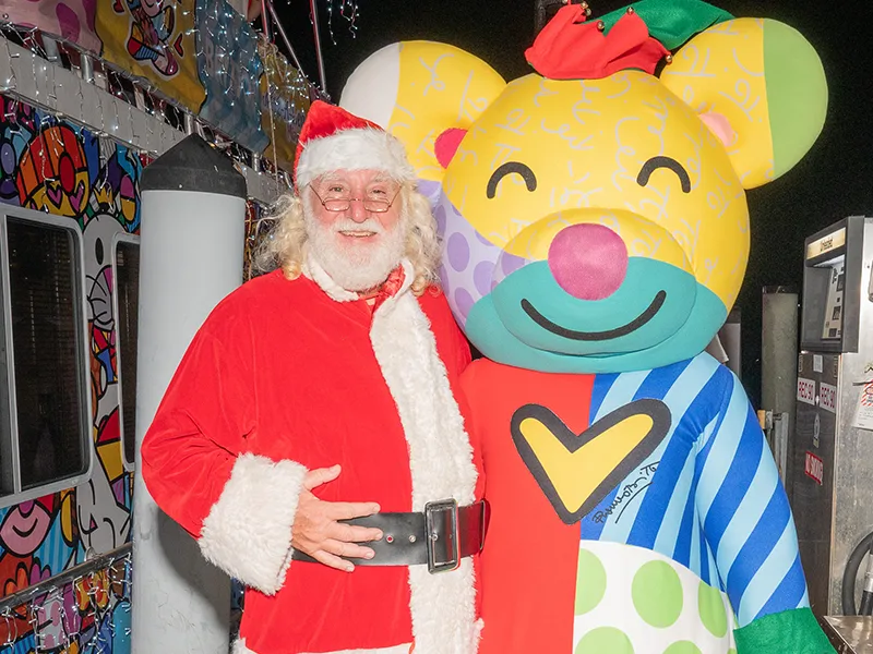 Santa Claus and a bear smiling at the camera, they are on a boat