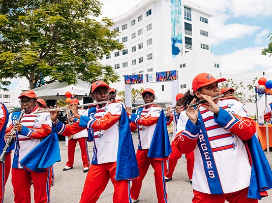 A group of people in uniform playing the flute and performing in the street.
