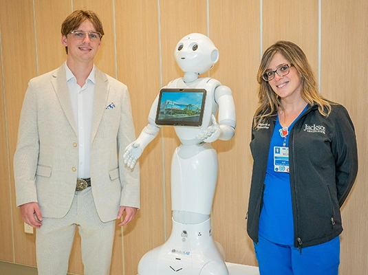 two people posing next to a white robot