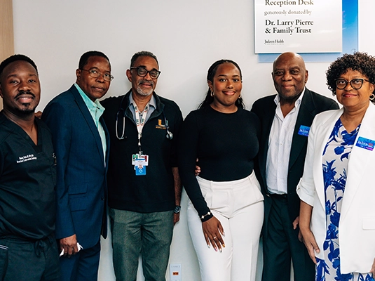 Six doctors dressed in suits posing and smiling at the camera during an event.