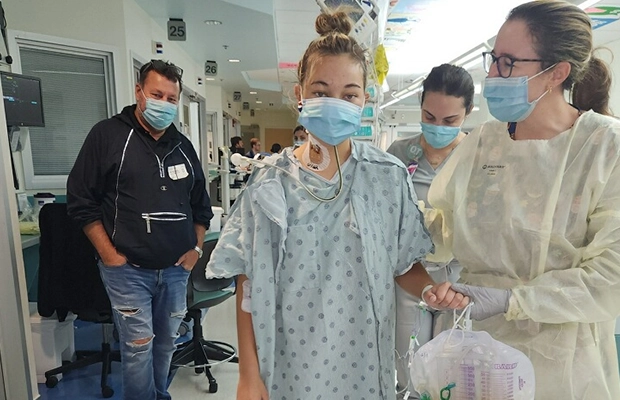 Young woman in a hospital gown standing next to a nurse.
