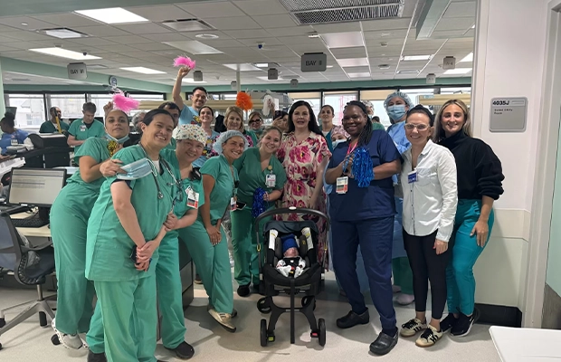 A large group of doctors alongside a small baby in a stroller.