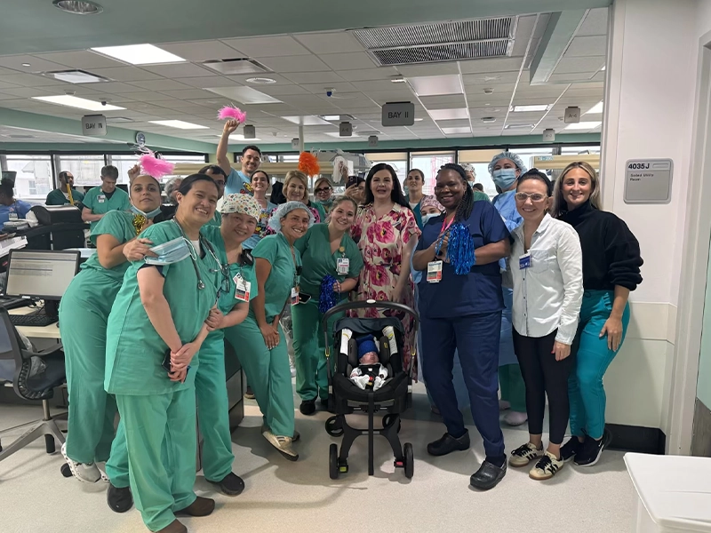 A large group of doctors alongside a small baby in a stroller.
