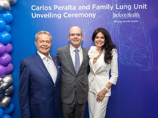 Three men and two women posing and smiling at the camera.