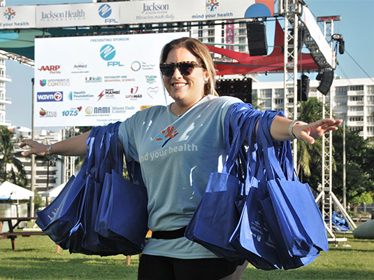 A woman holding on to multiple bags, she has on a light blue shirt