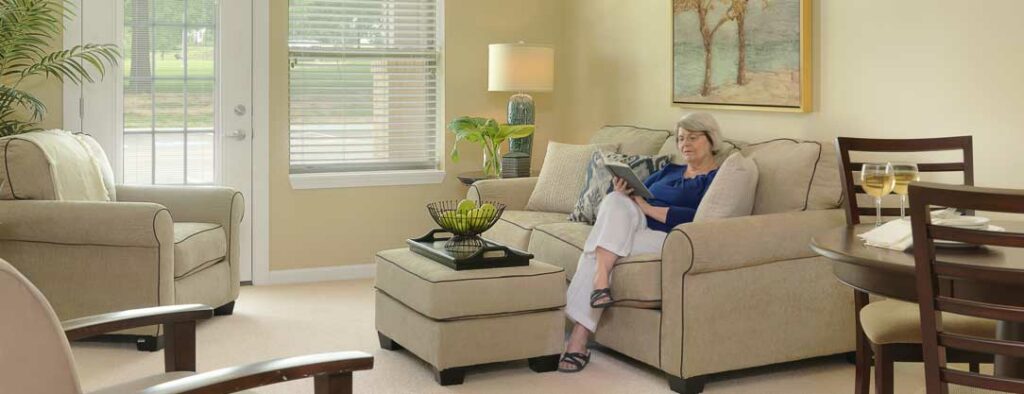 senior women sitting in her spacious senior apartment reading a book