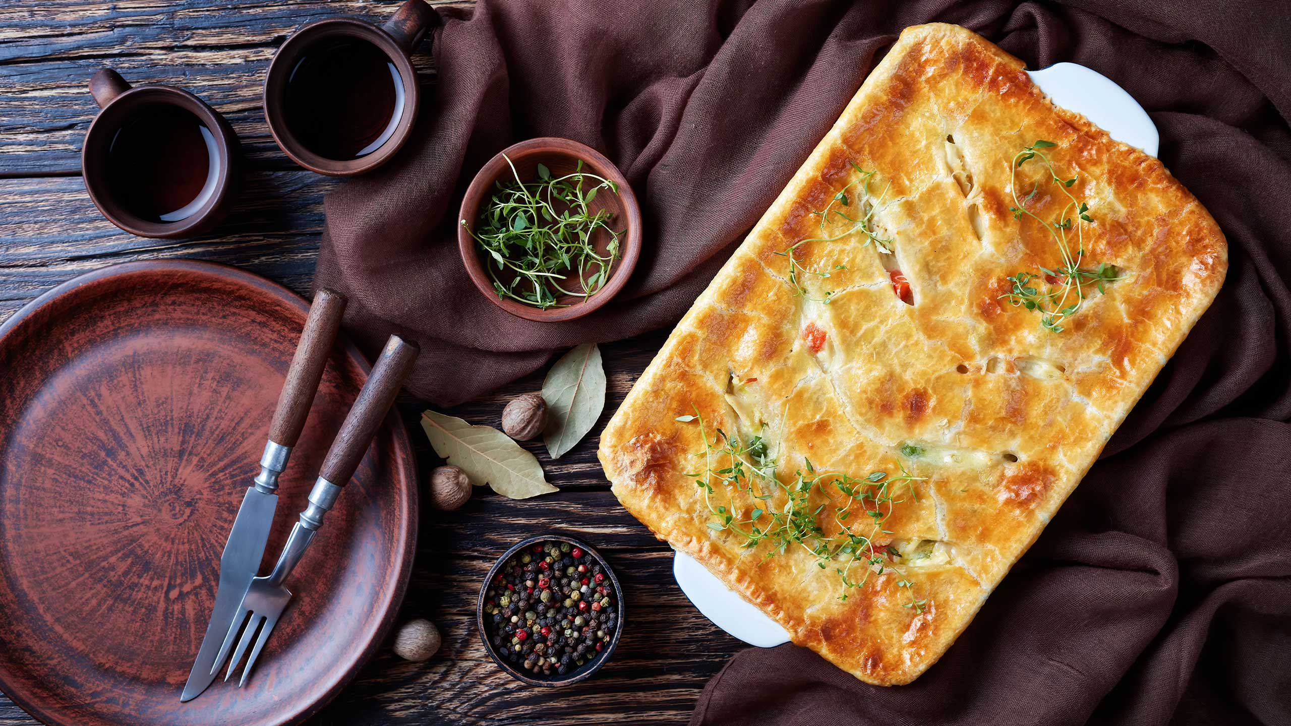 Tabuleiro de forno com empada feita com sobras de comida, sobre toalha de pano.