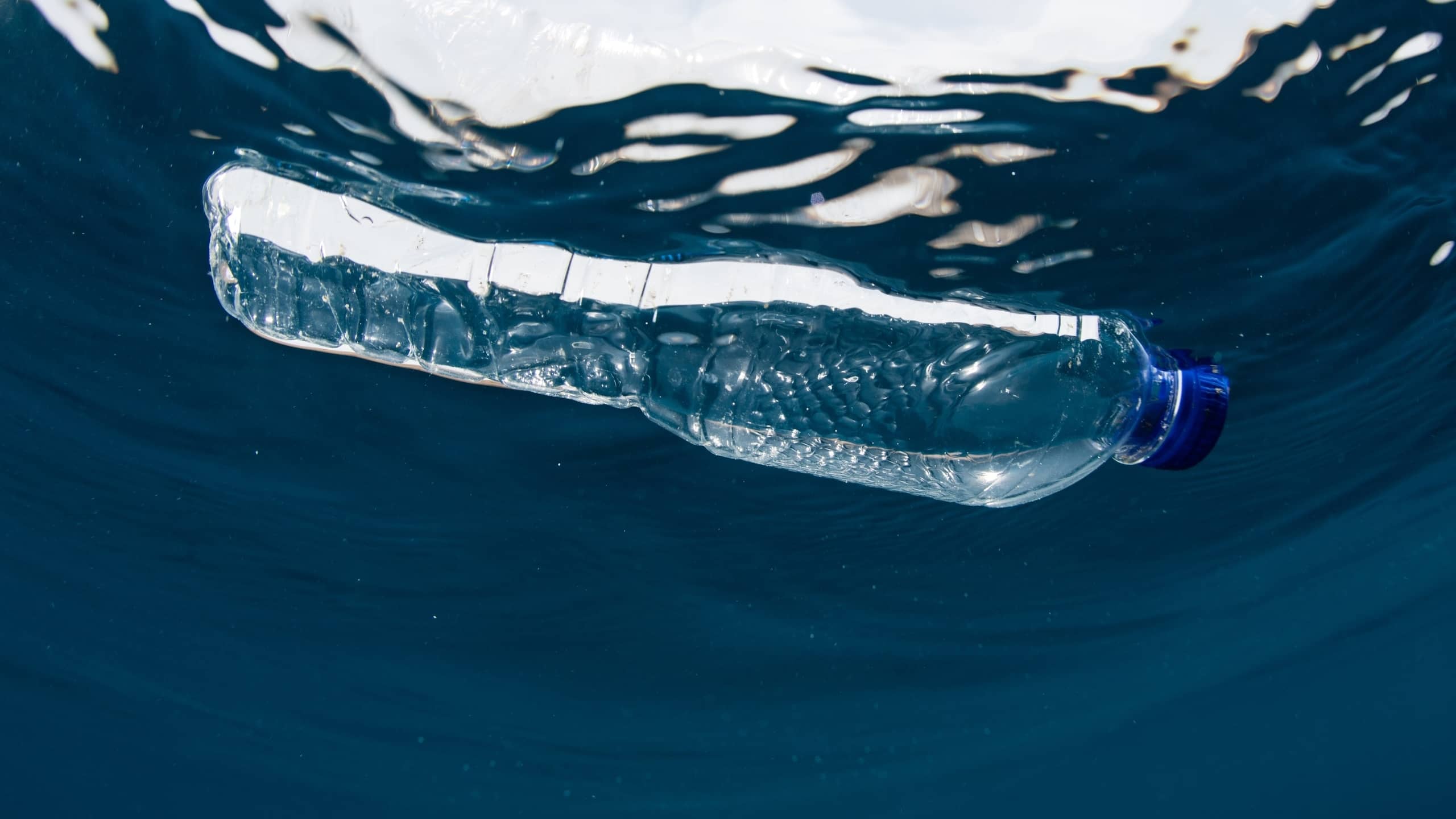 Garrafa de água de plástico usada, a boiar no mar.