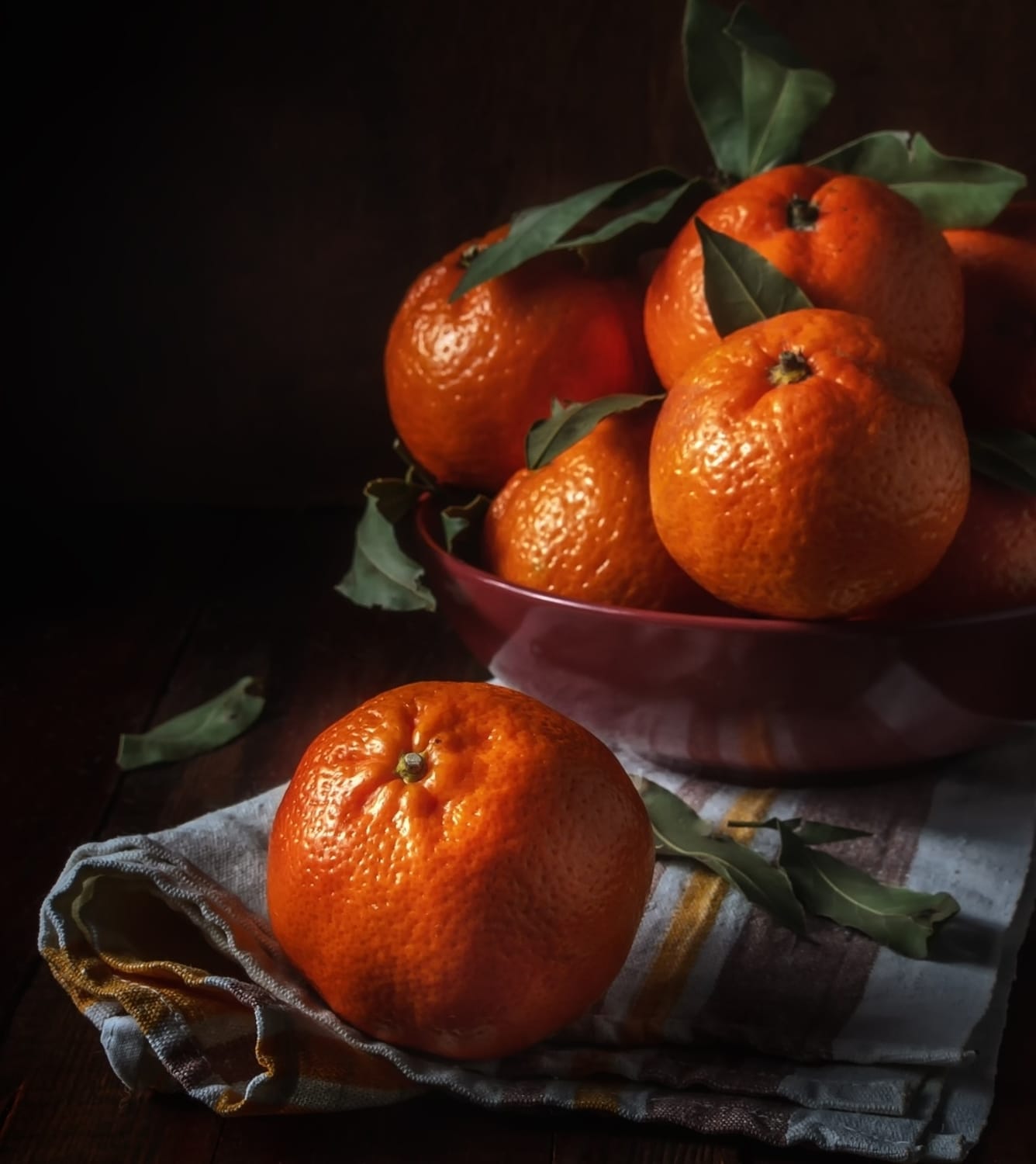 Taça com tangerinas sobre pano de cozinha.