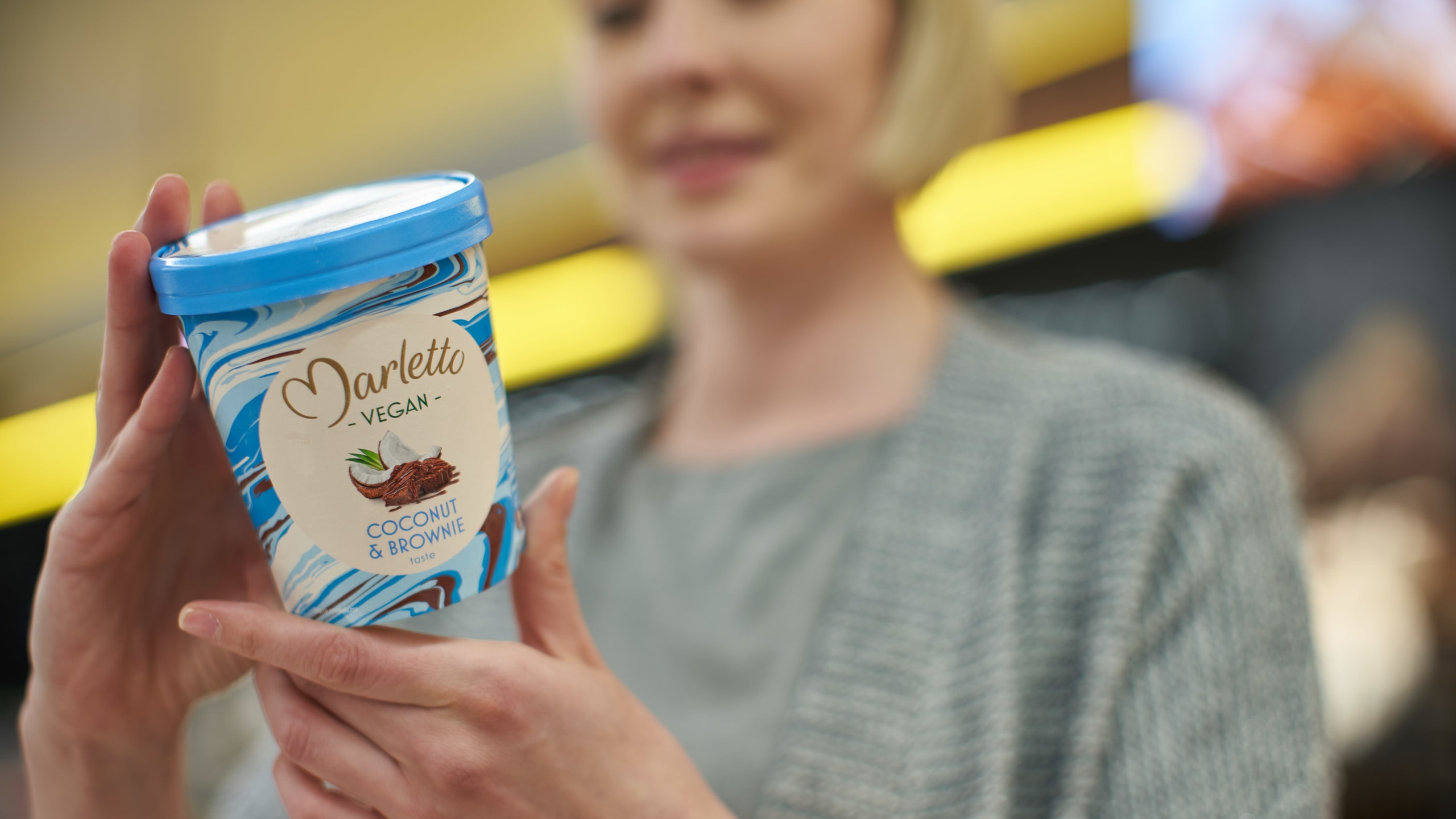 Woman in supermarket checking an ice cream pint label.