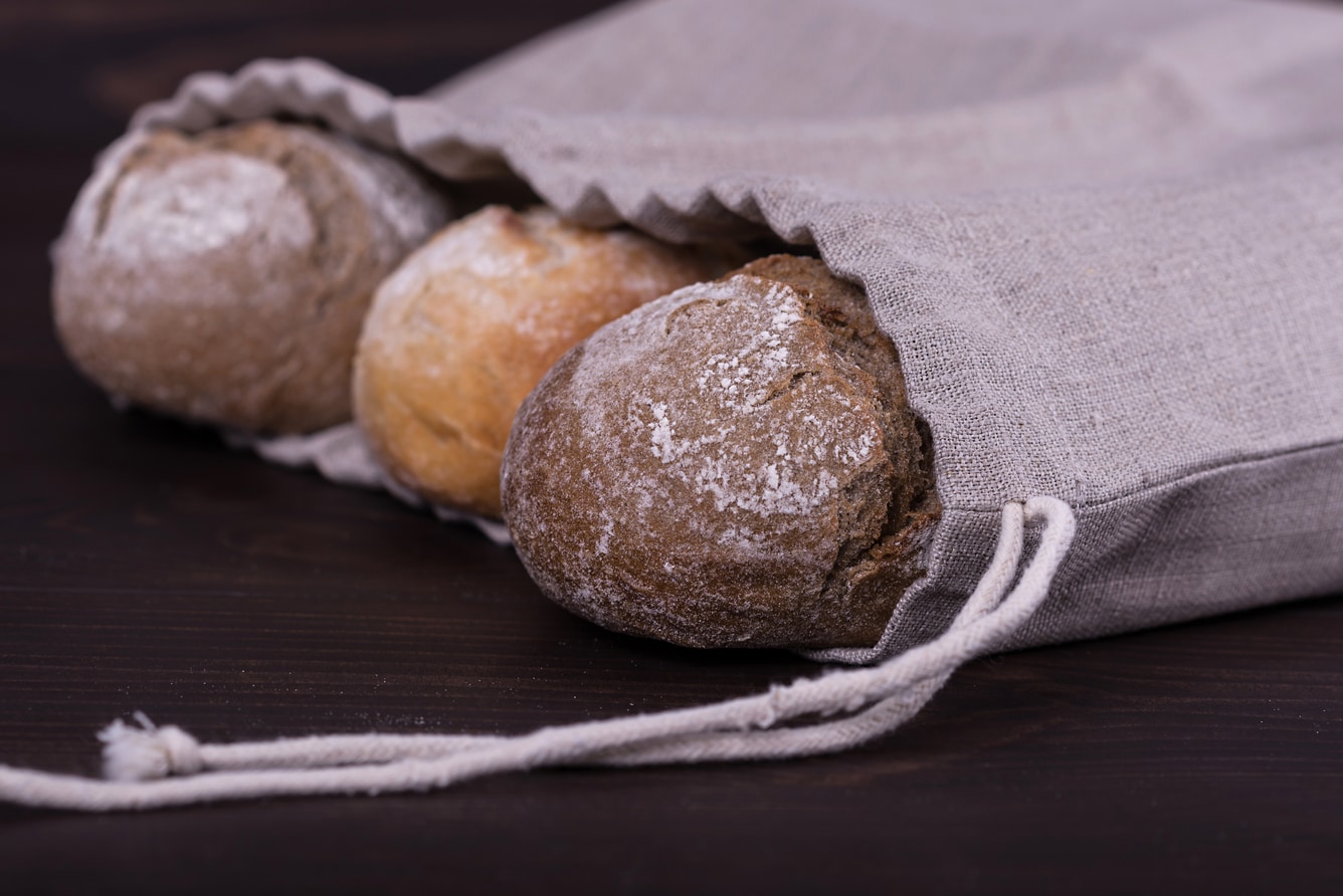 Saco de pano com pão sobre mesa.