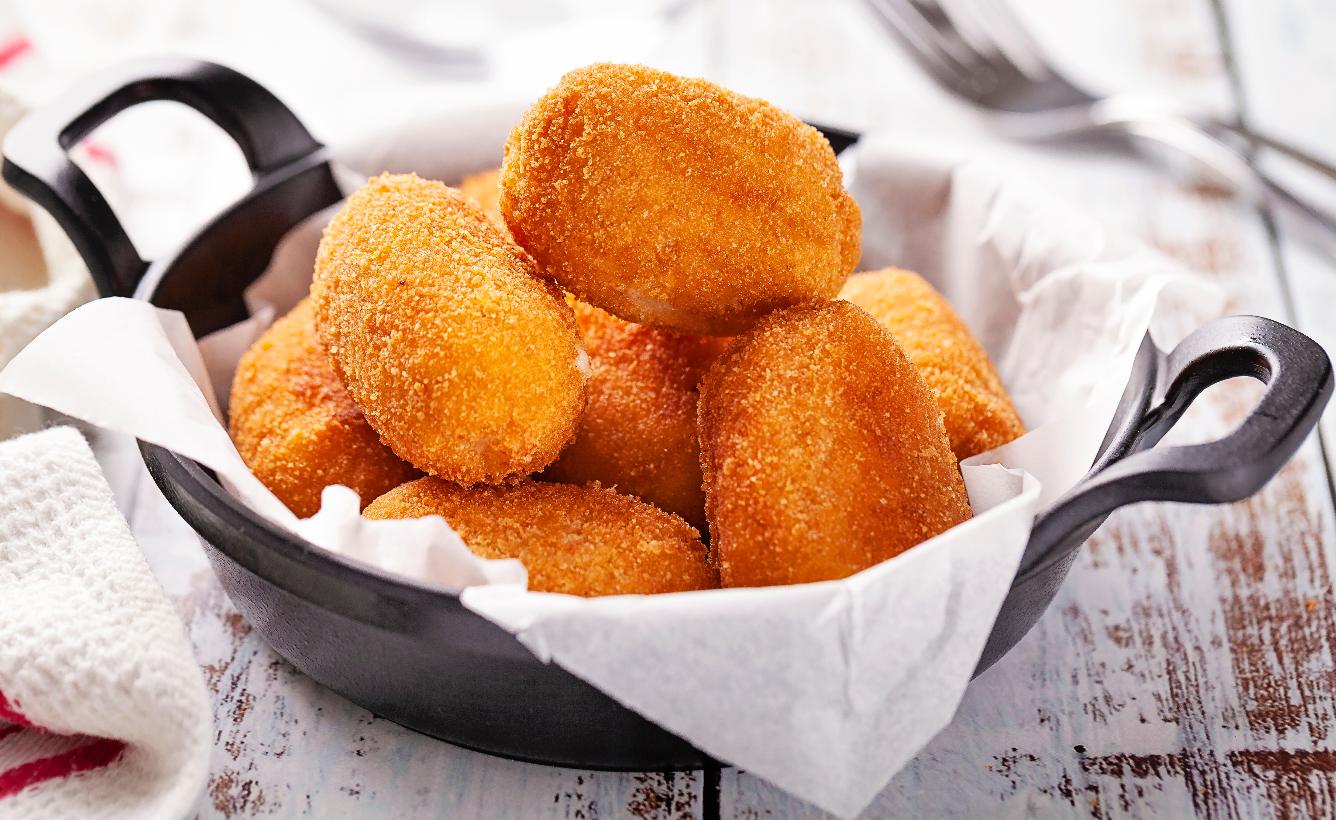 Iron recipient, with a sheet of parchment paper, with fried snacks.