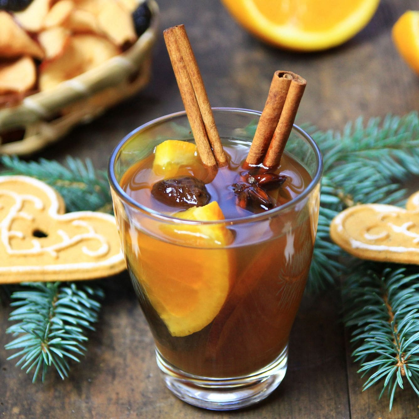 Copo com kompot, bebida de frutas secas, servida com paus de canela e rodelas de laranja.