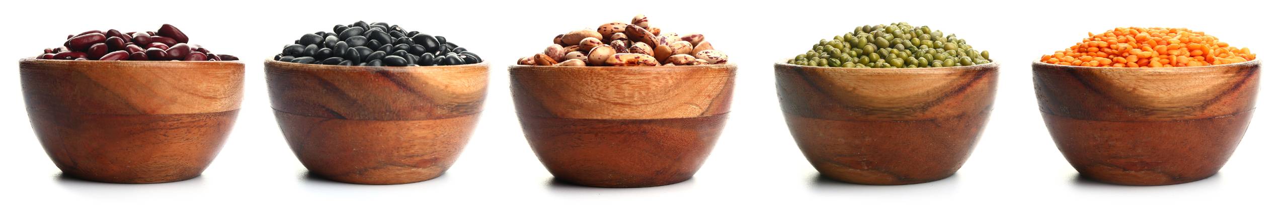 Pulses in wooden bowls: three types of beans, peas and lentils.