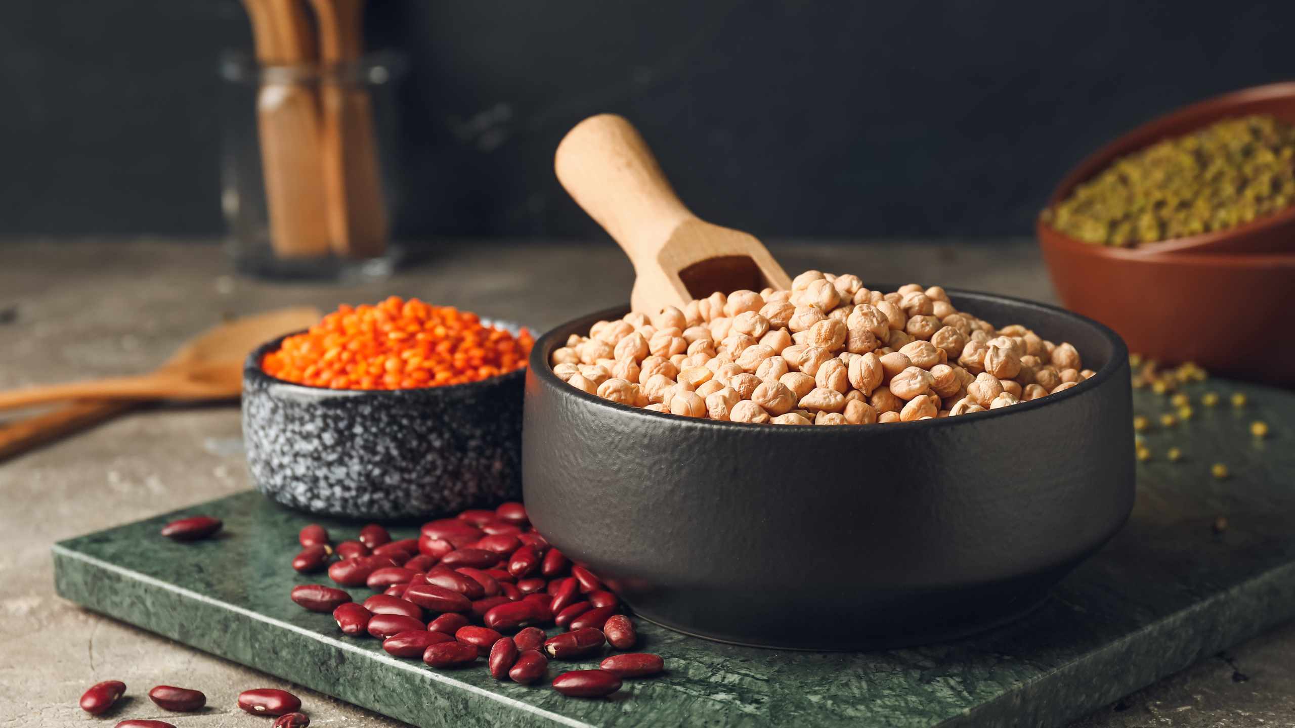 Bowls of pulses (lentils, beans, chickpeas and peas) over a marble board.