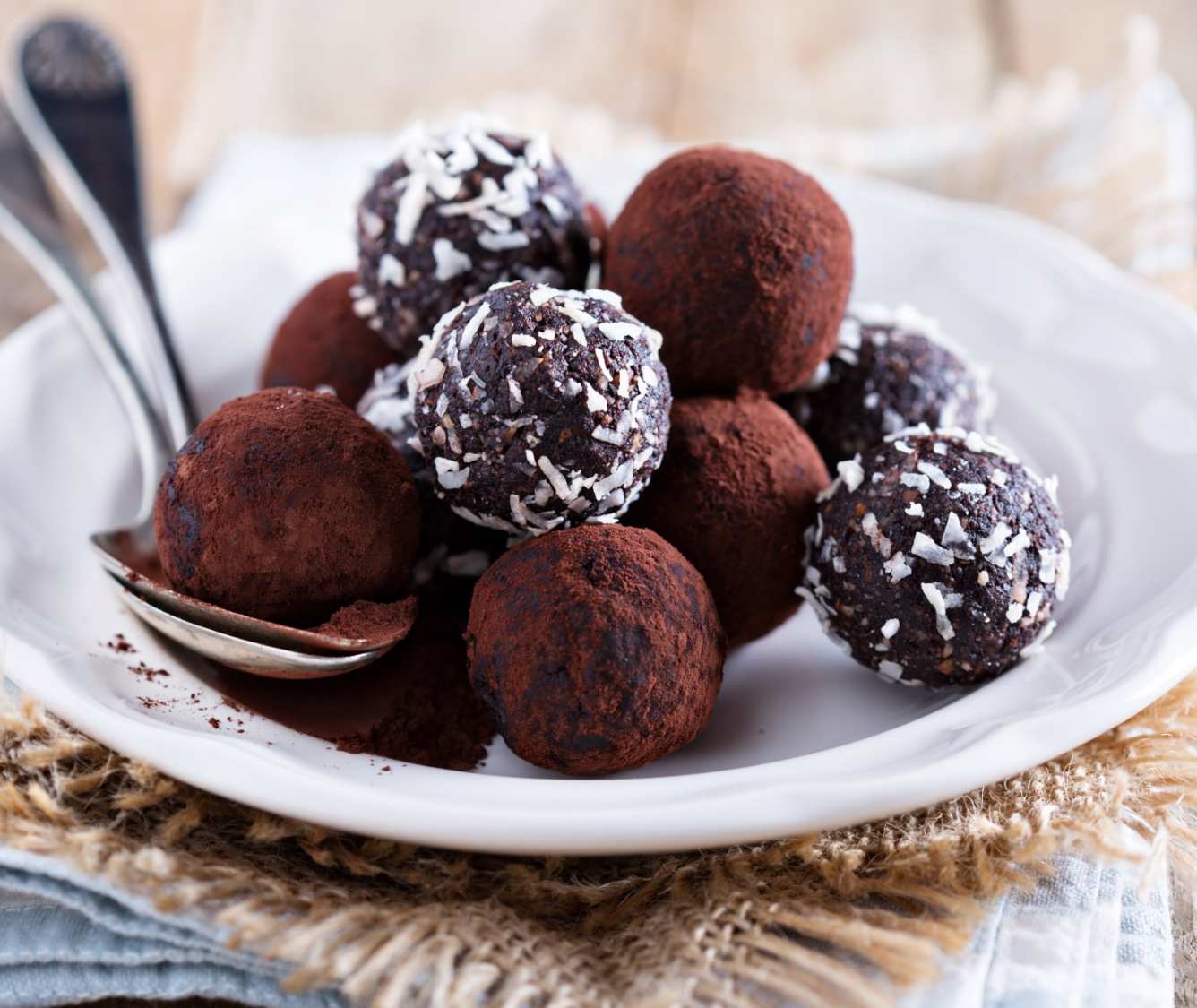 Prato com bombons e trufas caseiros sobre pano de serapilheira.