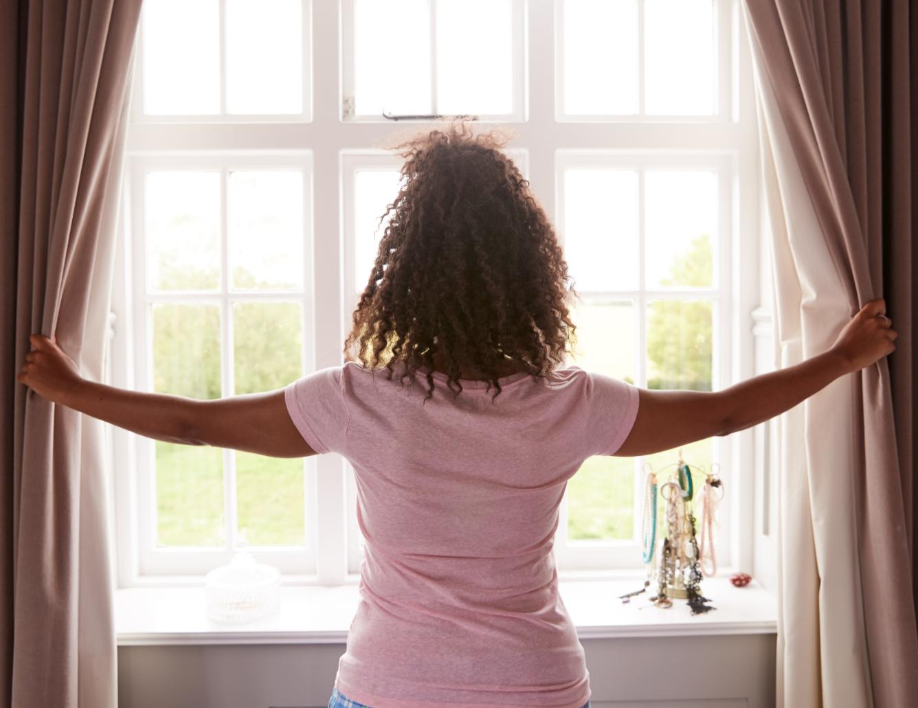 Woman opening the curtains.