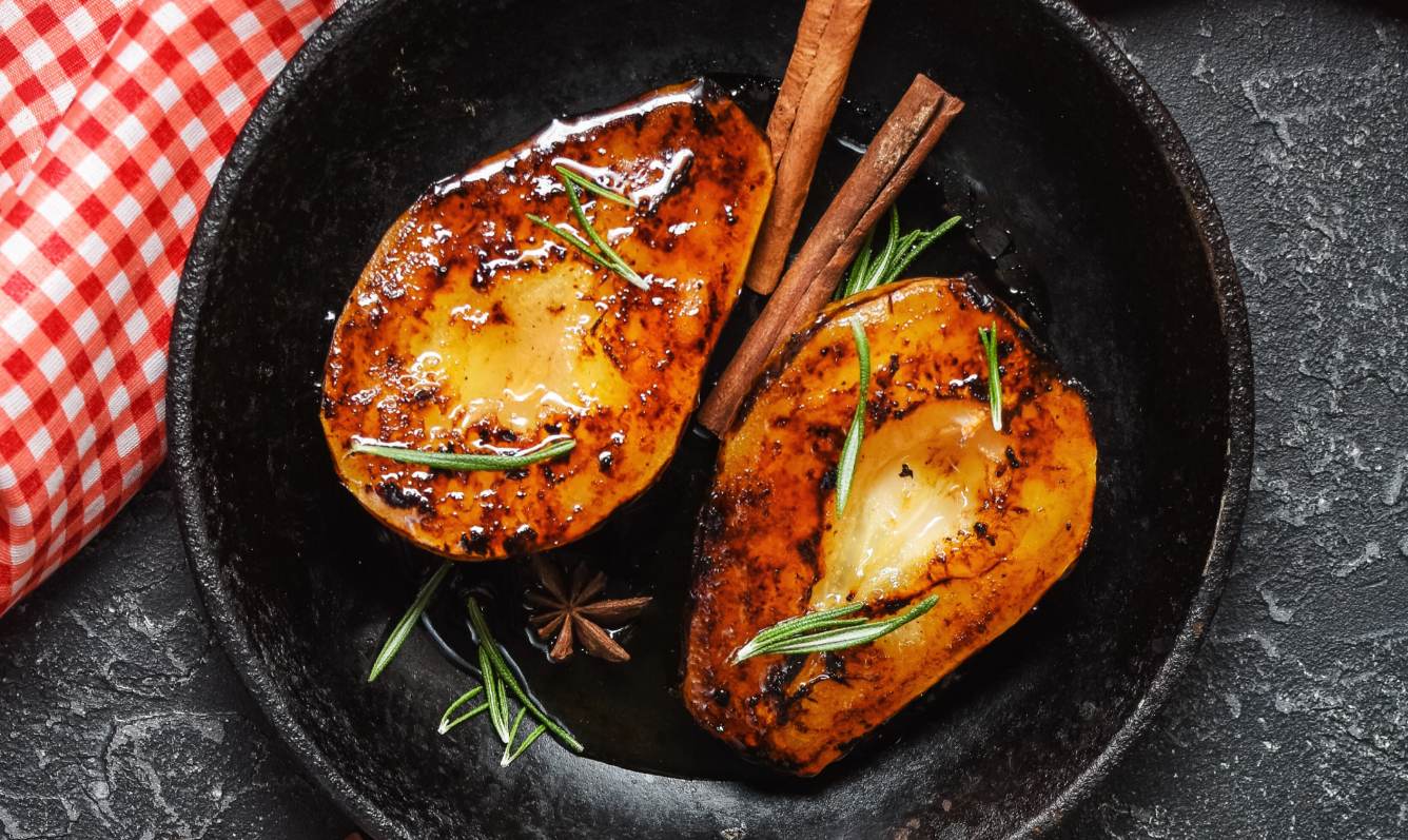 Sautéed pears in a pan with rosemary and cinnamon sticks.