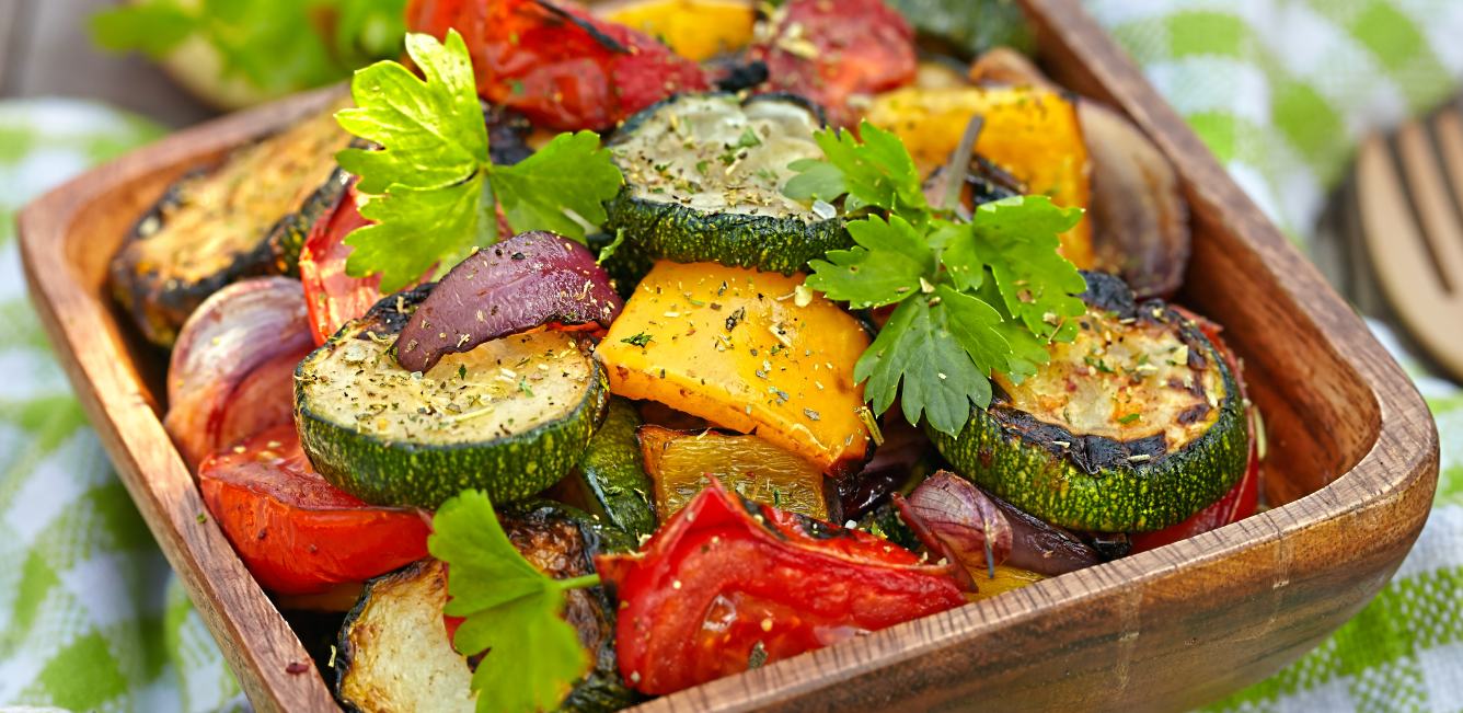 Grilled vegetables in a wooden bowl: tomato, courgette, pepper and onion.