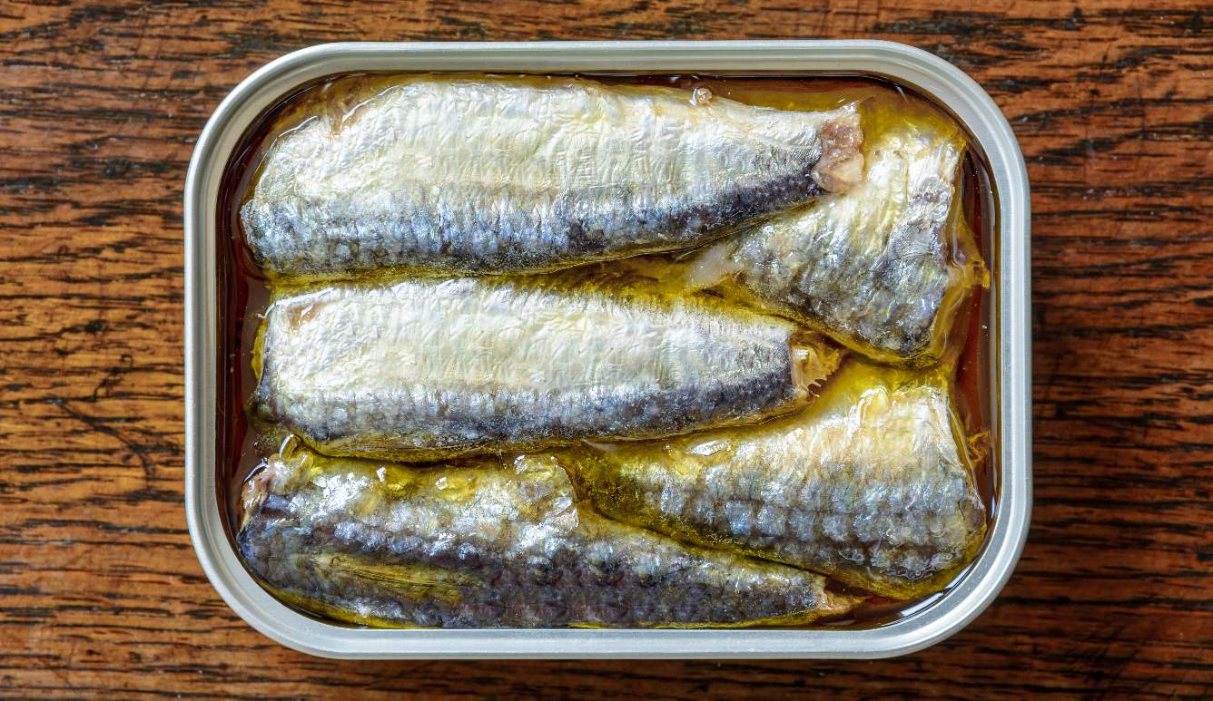 Can of sardines over a wooden table.