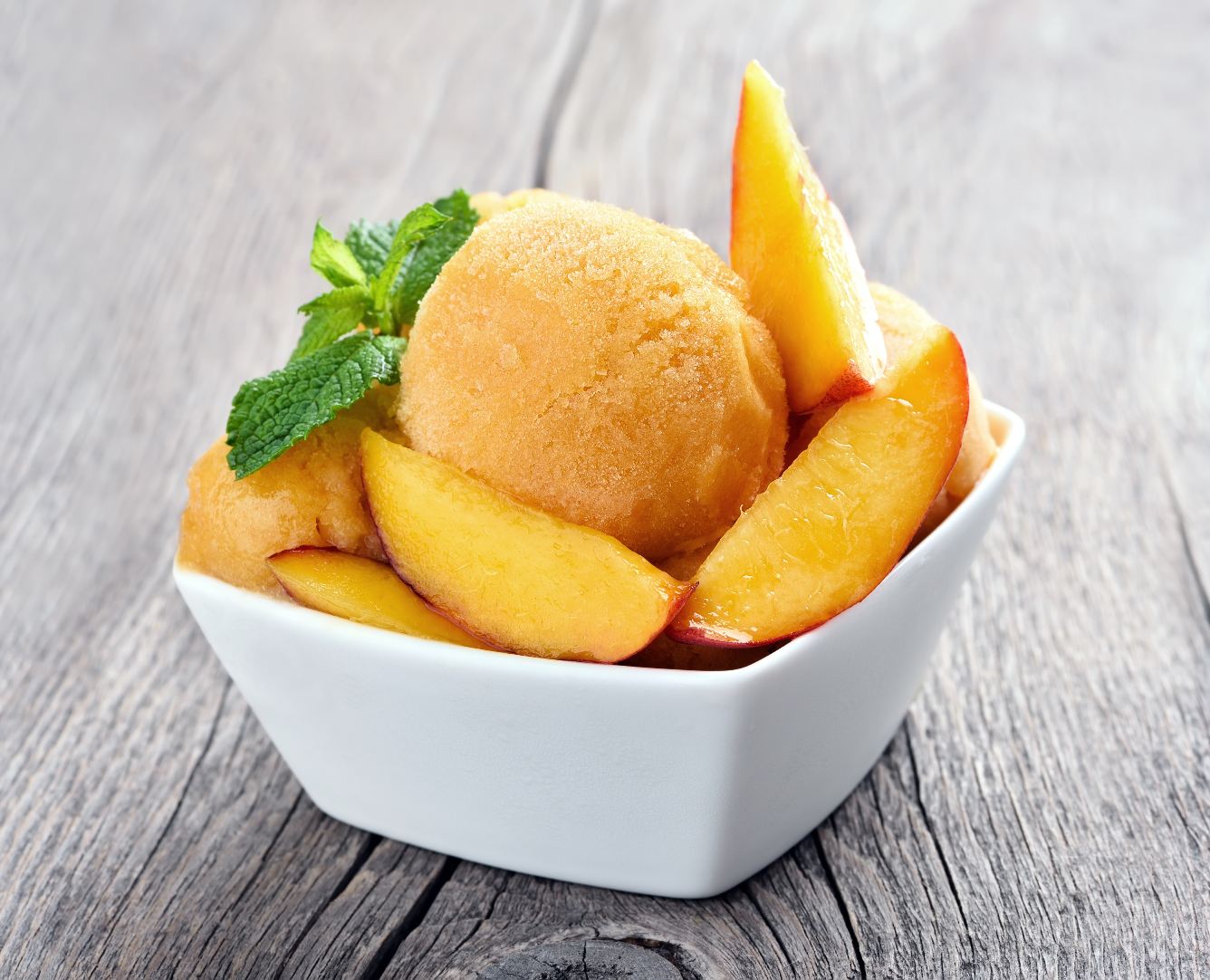 Peach sorbet in a bowl over a wooden table.