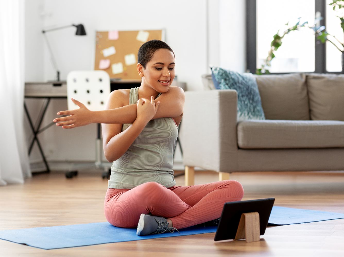 Woman exercising while looking at a tablet.