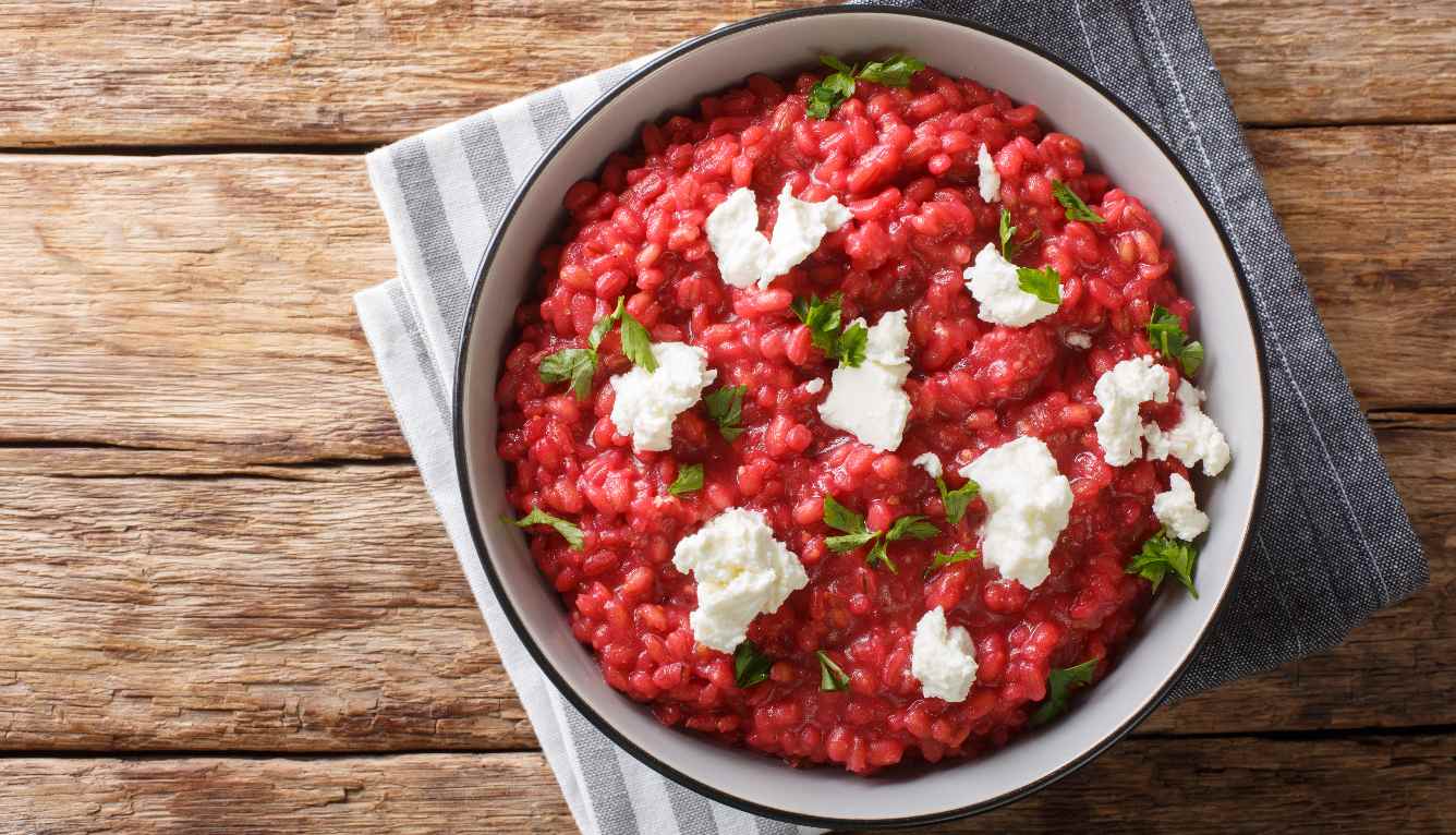 Bowl with beetroot risotto with fresh cheese and basil.