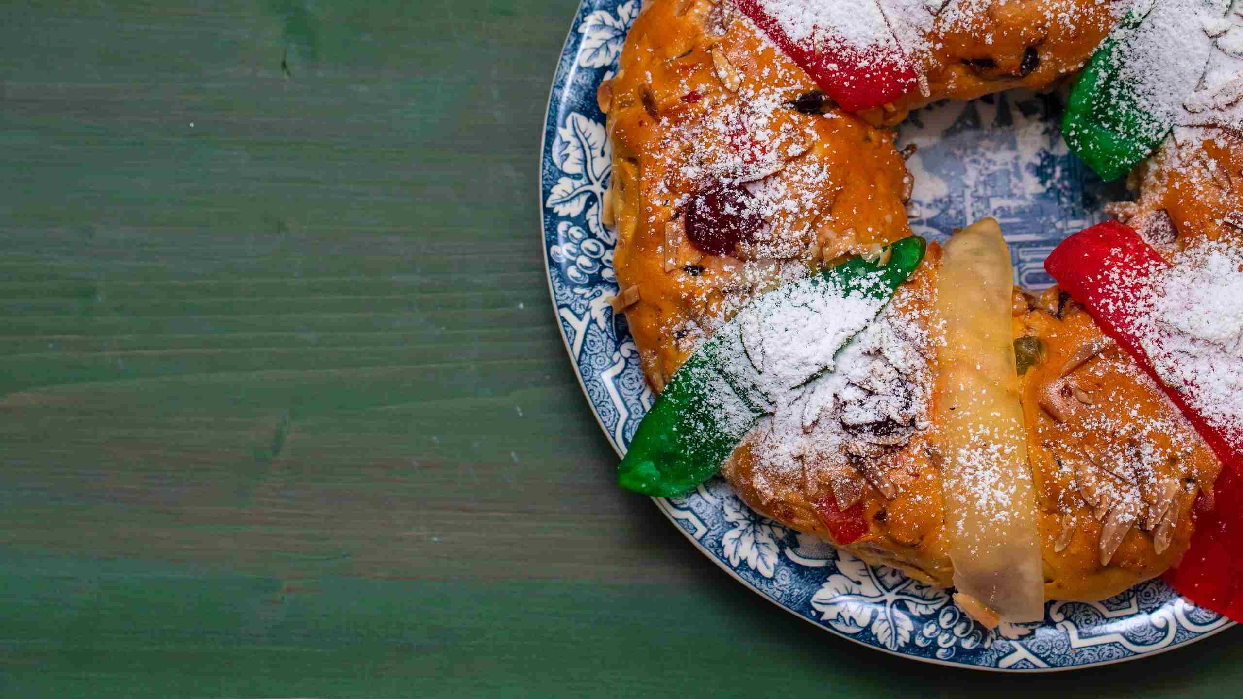 Bolo-rei (King Cake) in ceramic dish on a wooden table.