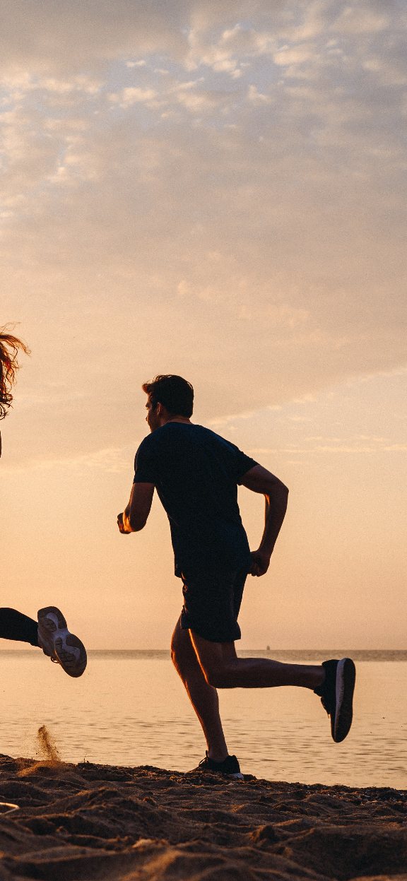 Men and woman running in the beach.