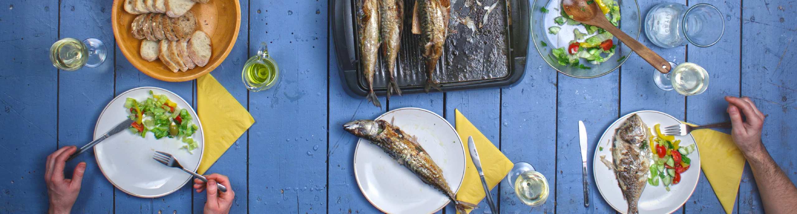 Mesa posta com peixe grelhado e salada.