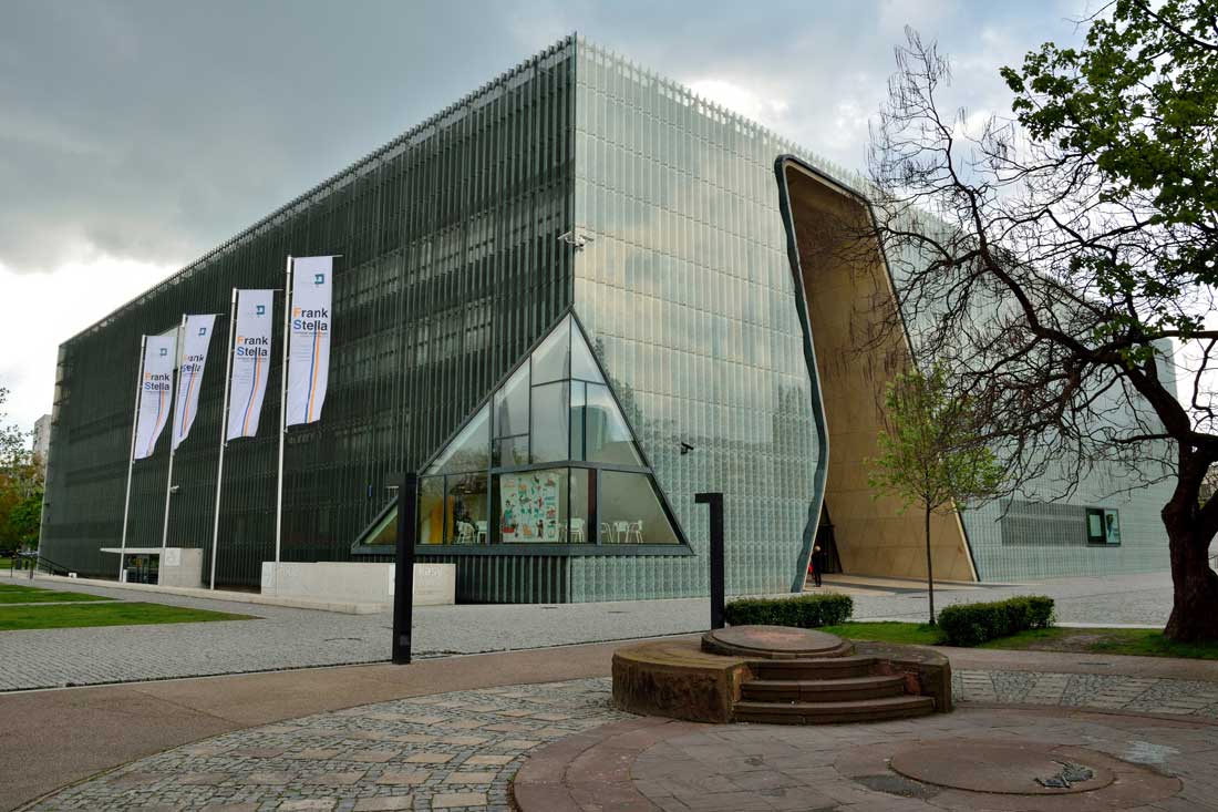 Exterior view of the Museum of History of Polish Jews, in Warsaw, with Ghetto Heroes Monument and people.